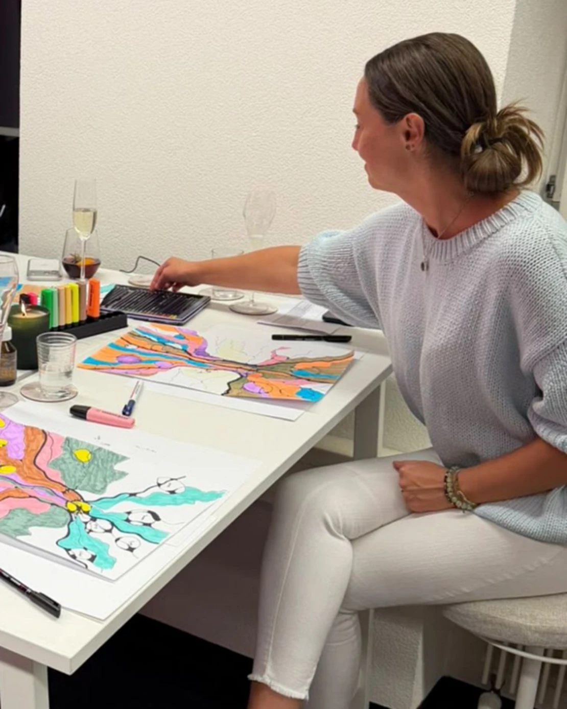 Ramunė Bauer at the table during the evening, next to colourful tree drawings and a lit candle